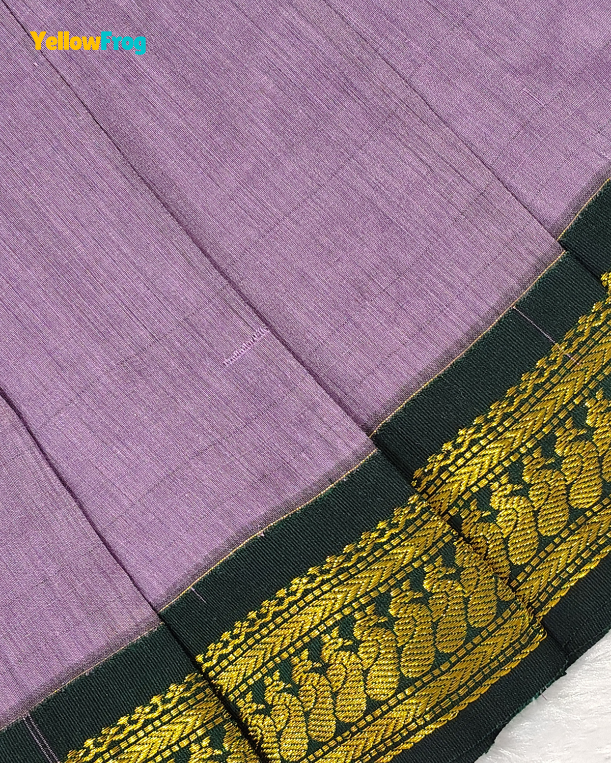 A close-up of a lavender purple woven fabric, likely a saree, featuring a wide dark green border with intricate gold paisley and floral zari embroidery. A 'YellowLong' brand watermark is visible in the top left corner.