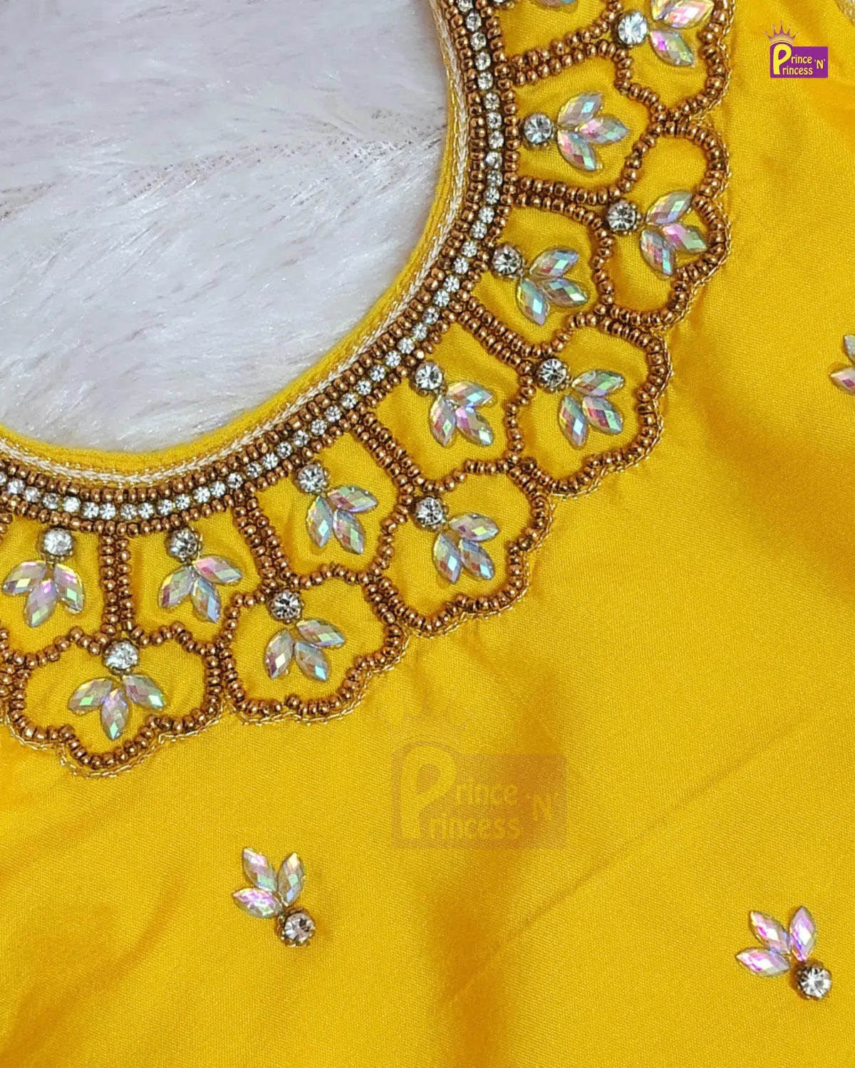 Close-up of a bright yellow fabric garment with ornate gold beaded neckline embroidery, iridescent floral embellishments, and small matching floral details on the fabric.