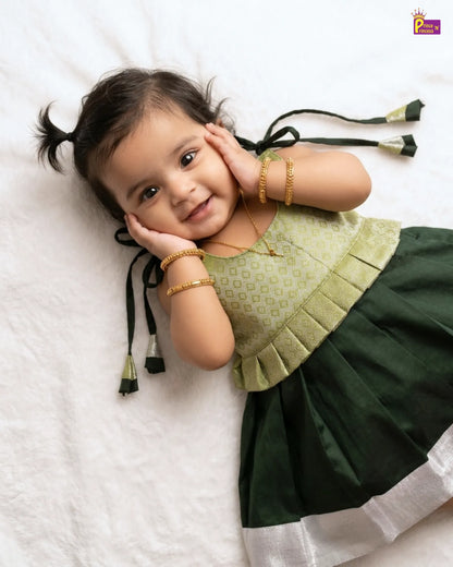 Child wearing a green and white traditional outfit with gold jewelry on a white background