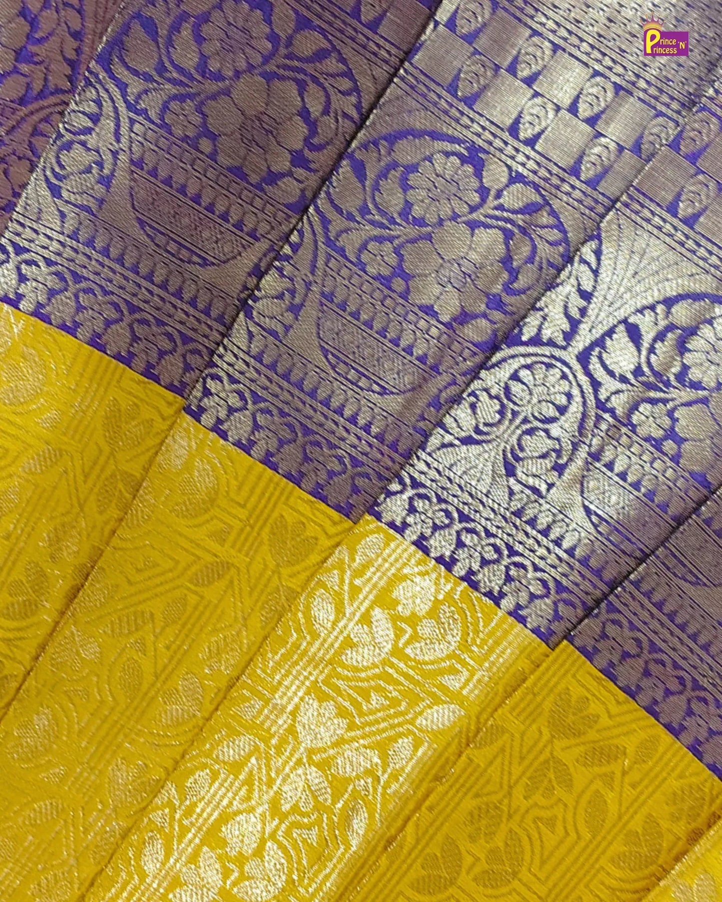A close-up of a folded silk saree fabric showing a purple and silver brocade pattern on the upper portion and a bright yellow lower portion with matching metallic woven motifs.
