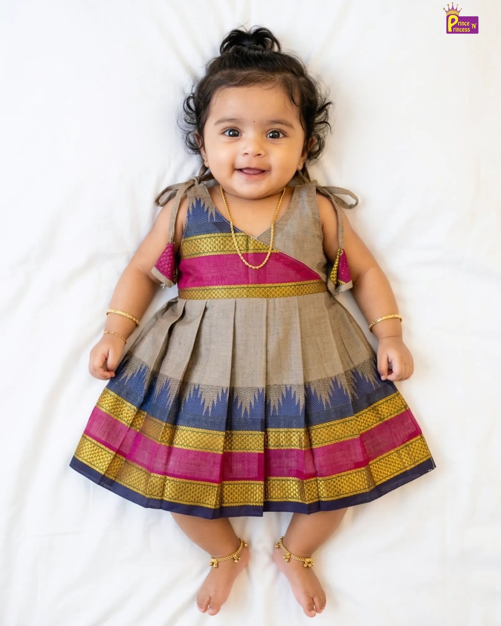Baby wearing a colorful traditional dress on a white background