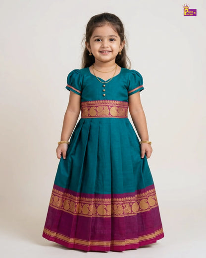 Young girl wearing a traditional teal and purple dress with gold patterns on a white background