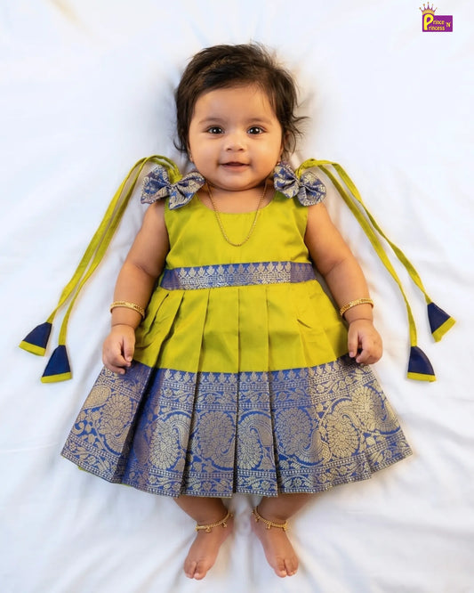 Baby wearing a green and blue dress with decorative elements on a white background