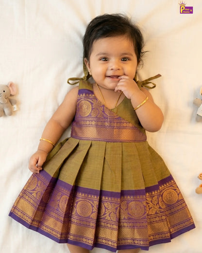 Baby wearing a green and purple traditional dress on a white background