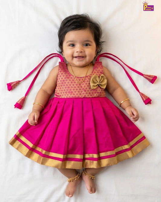 Baby wearing a pink traditional outfit with gold accents on a white background