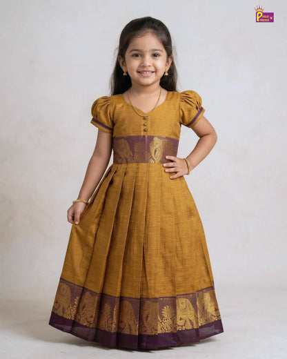 Young girl wearing a mustard yellow dress with brown accents on a white background