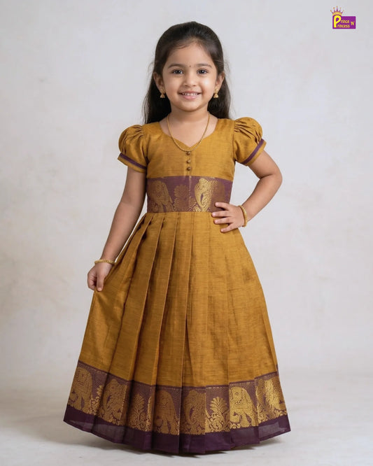 Young girl wearing a mustard yellow dress with brown accents on a white background