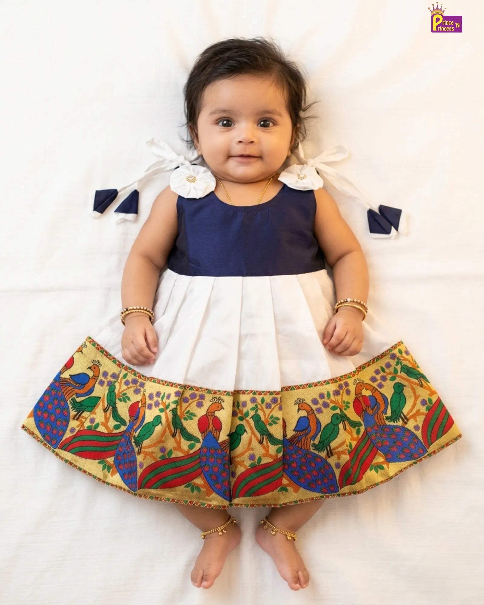 Baby wearing a traditional outfit with a colorful skirt on a white background