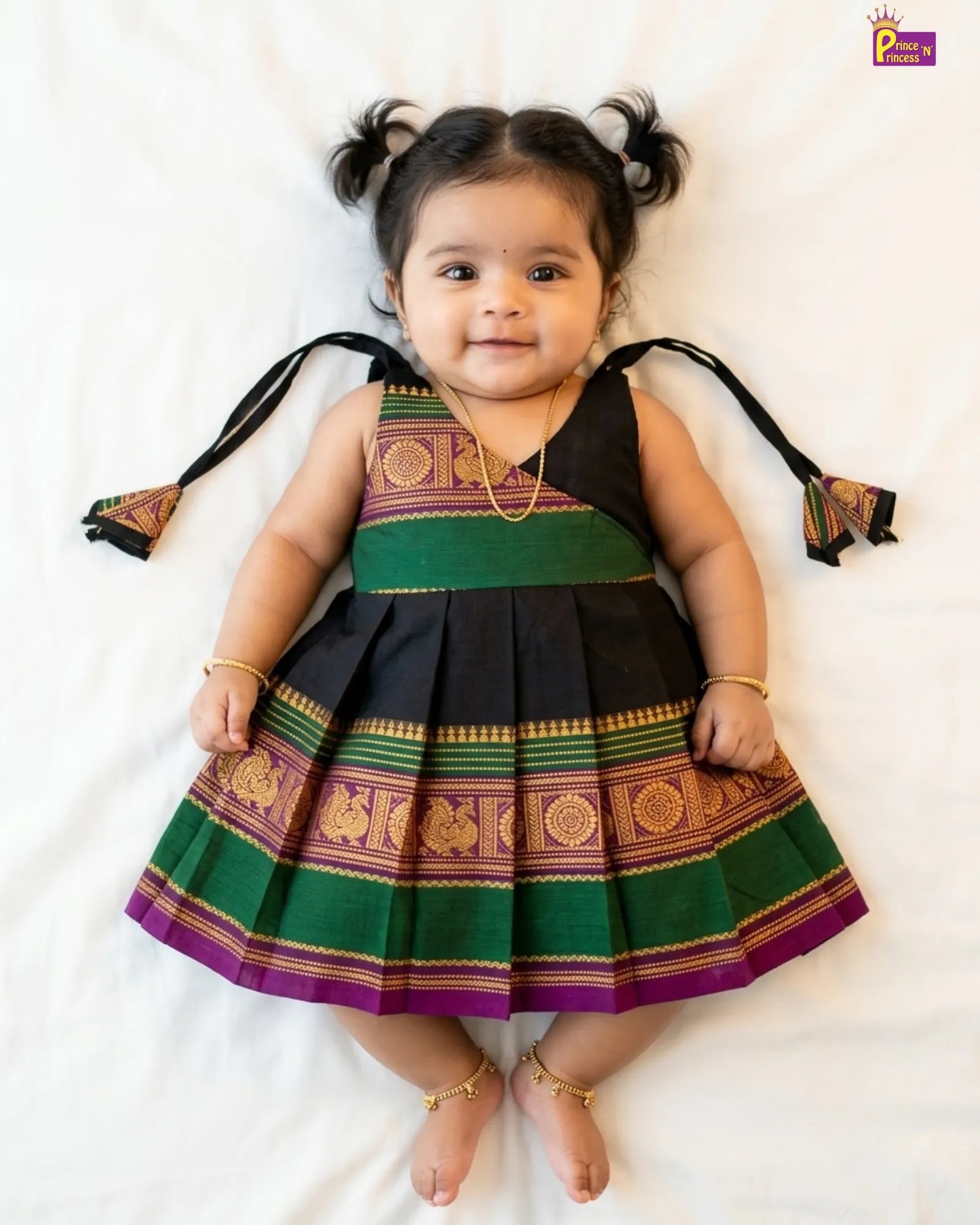 Child wearing a traditional outfit with green, purple, and black colors on a white background