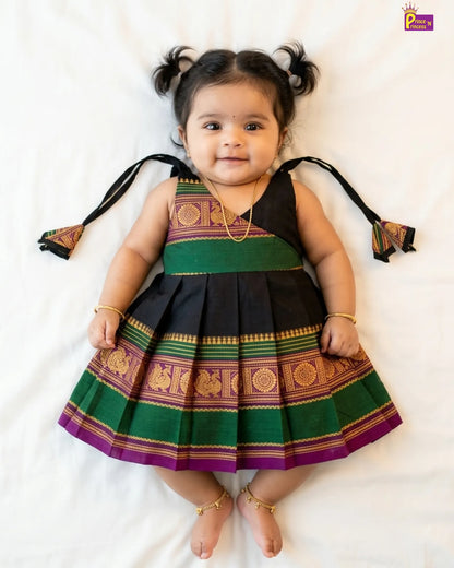 Child wearing a traditional outfit with green, purple, and black colors on a white background