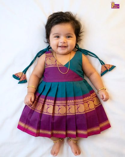 Baby wearing a traditional outfit with purple and green colors on a white background