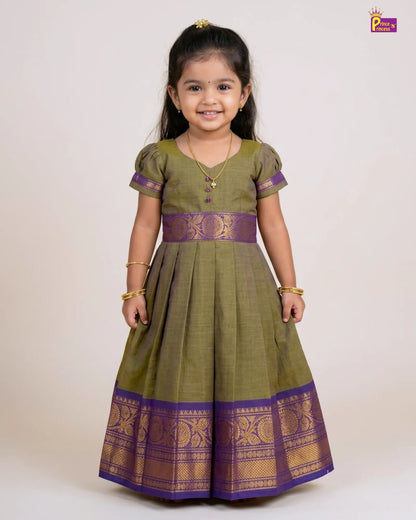 Young girl wearing a green and purple traditional dress on a white background