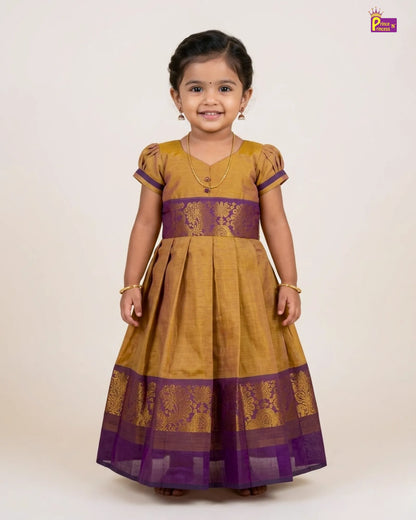 Young girl wearing a mustard yellow and purple traditional dress on a white background