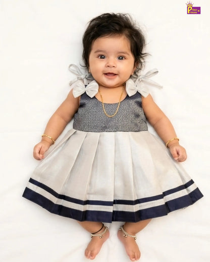 Baby wearing a dress with white ruffled sleeves and a navy blue trim on a white background
