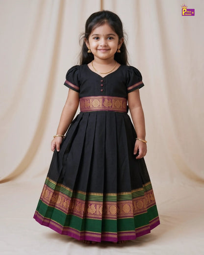 Young girl wearing a black traditional dress with colorful patterns on a beige background