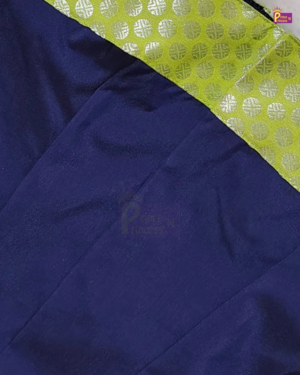 A close-up of a dark navy blue fabric, likely silk, with a contrasting lime green border featuring a silver metallic geometric pattern.