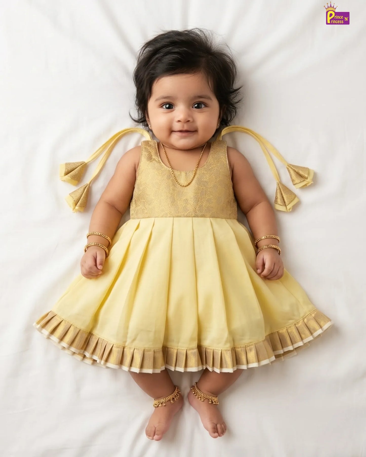 Baby wearing a yellow dress with tassels on a white background