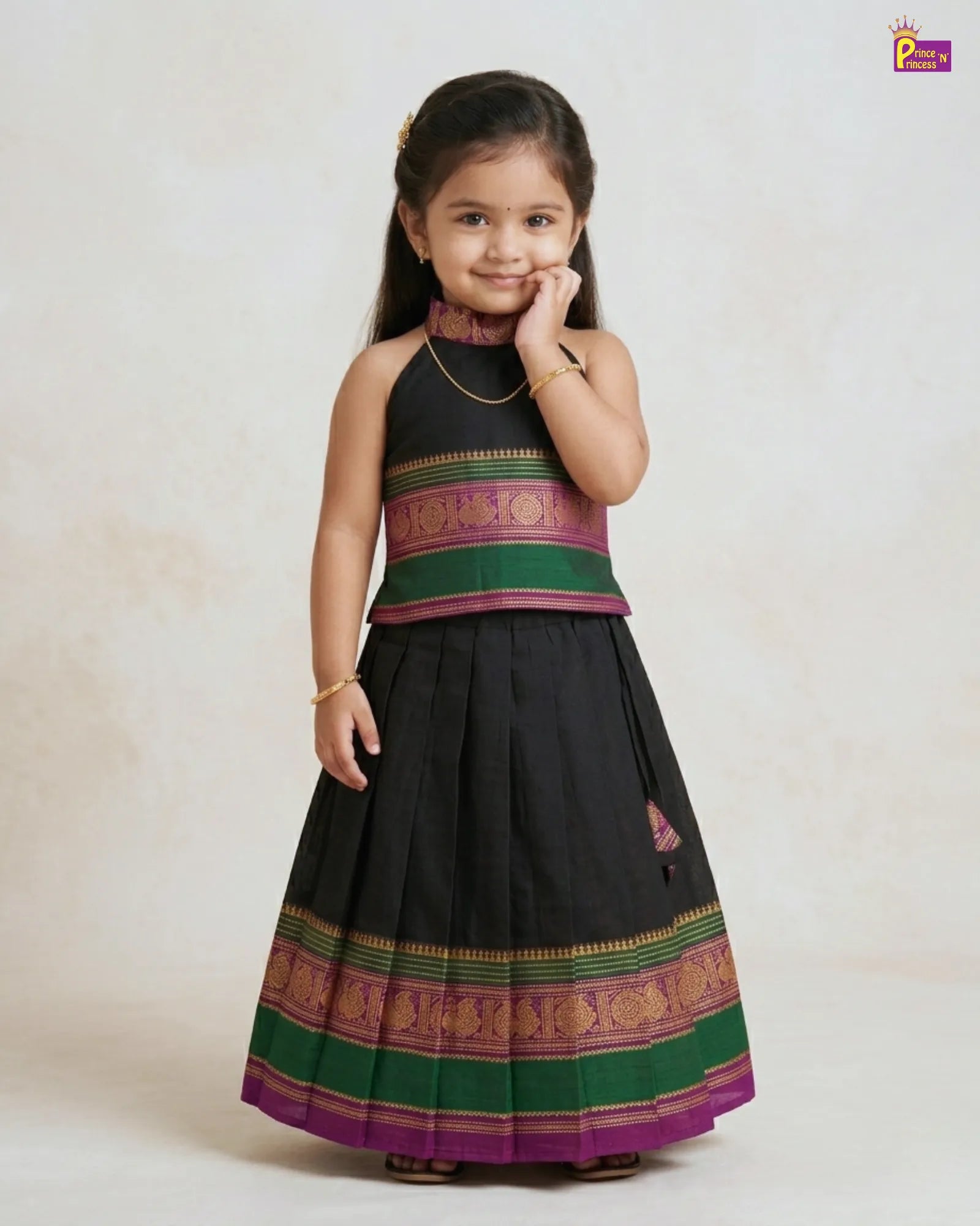 Young girl wearing a traditional black and green dress with colorful patterns on a white background