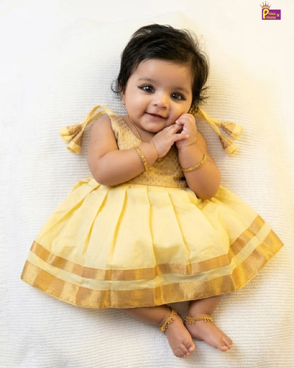 Baby in a yellow dress lying on a white surface