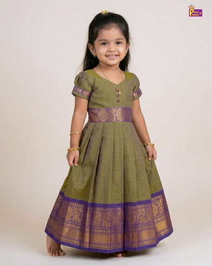 Young girl wearing a green and purple traditional dress on a white background