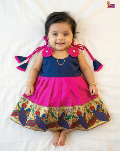 Baby wearing a colorful traditional outfit with a patterned skirt on a white background