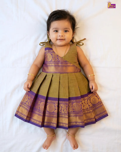 Baby wearing a traditional outfit with purple and gold patterns on a white background