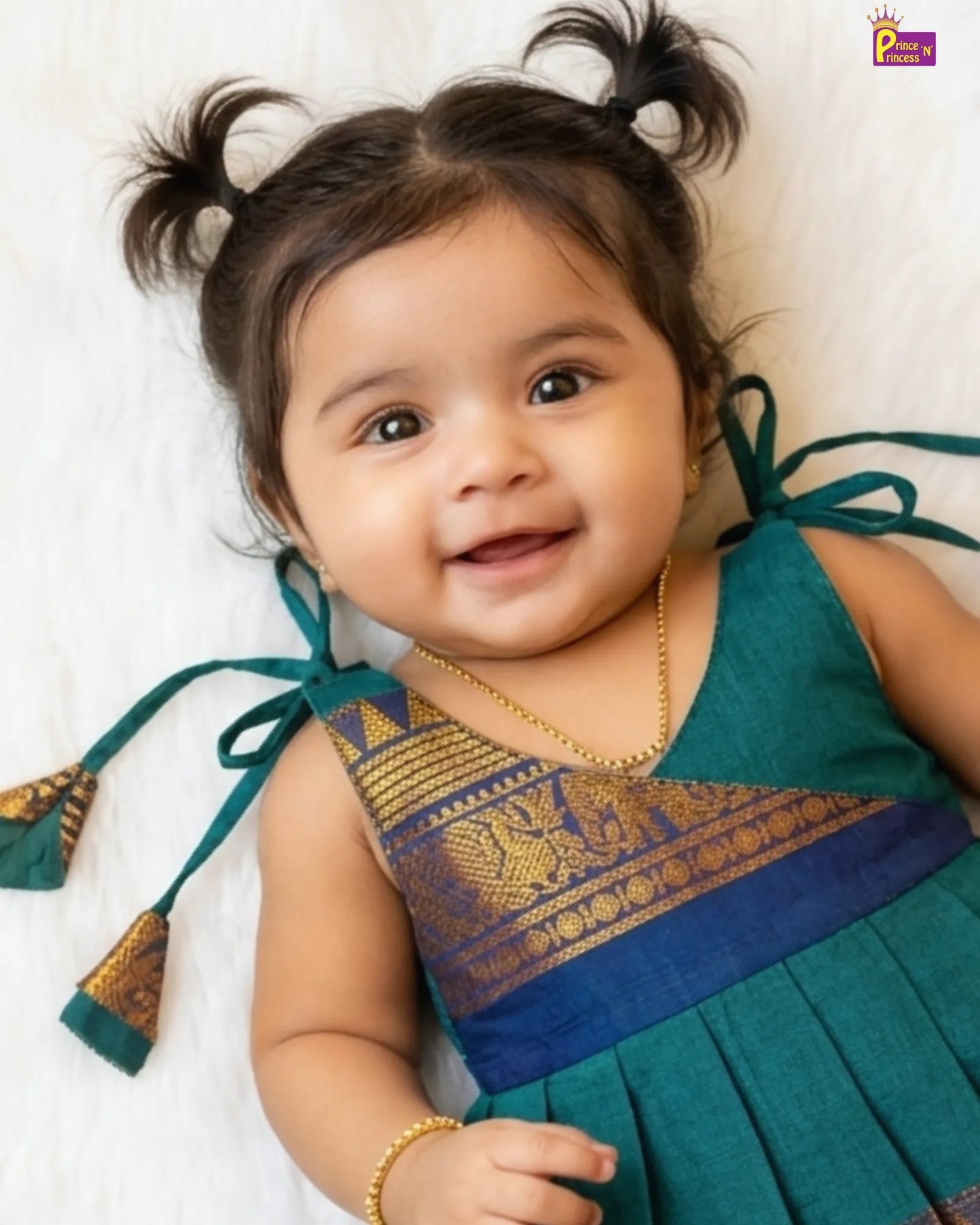Baby wearing a traditional outfit with green and blue colors on a white background