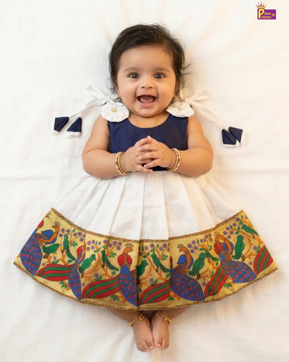 Baby wearing a traditional outfit with a colorful skirt on a white background