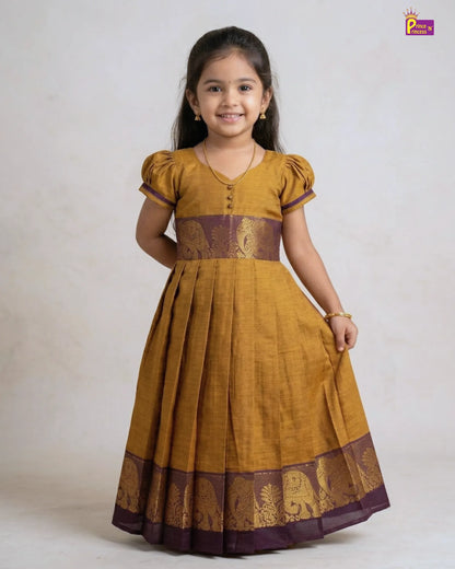 Young girl wearing a mustard yellow dress with brown accents on a white background