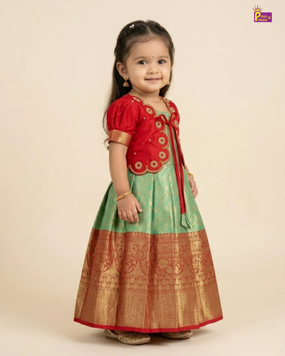 Child wearing a red and green traditional outfit on a beige background