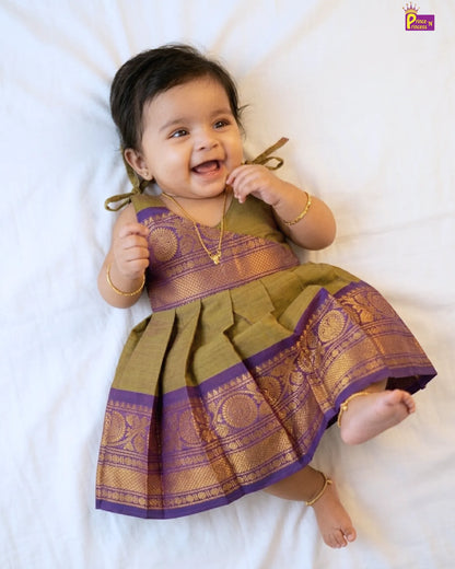 Baby wearing a traditional outfit with green and purple colors on a white background