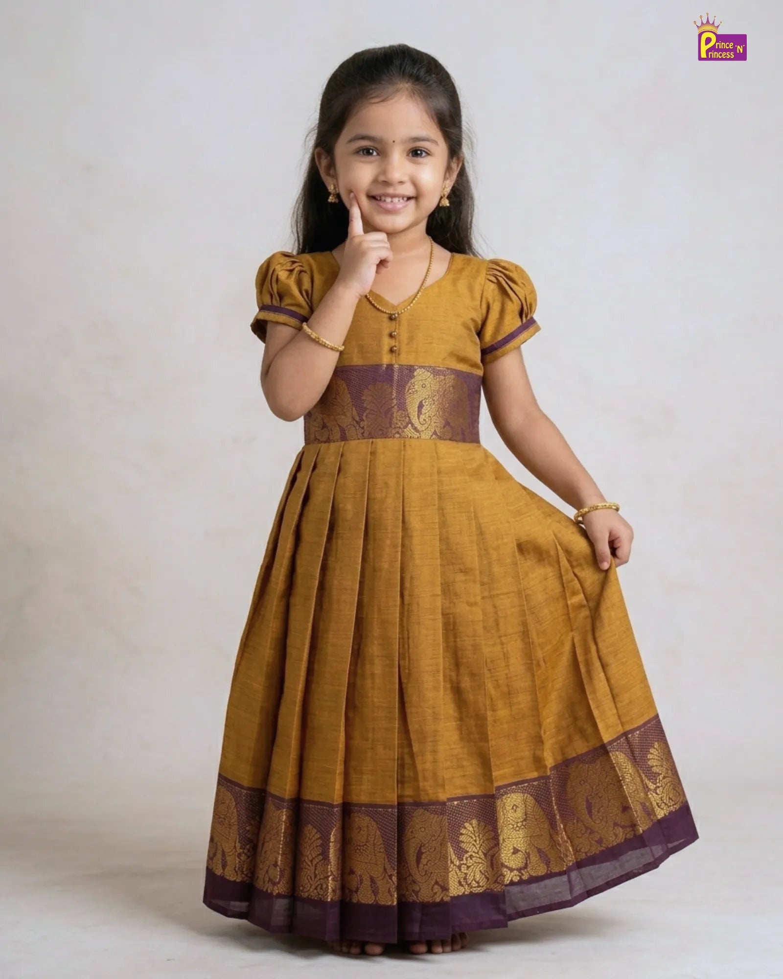 Young girl wearing a mustard yellow dress with purple accents on a plain background