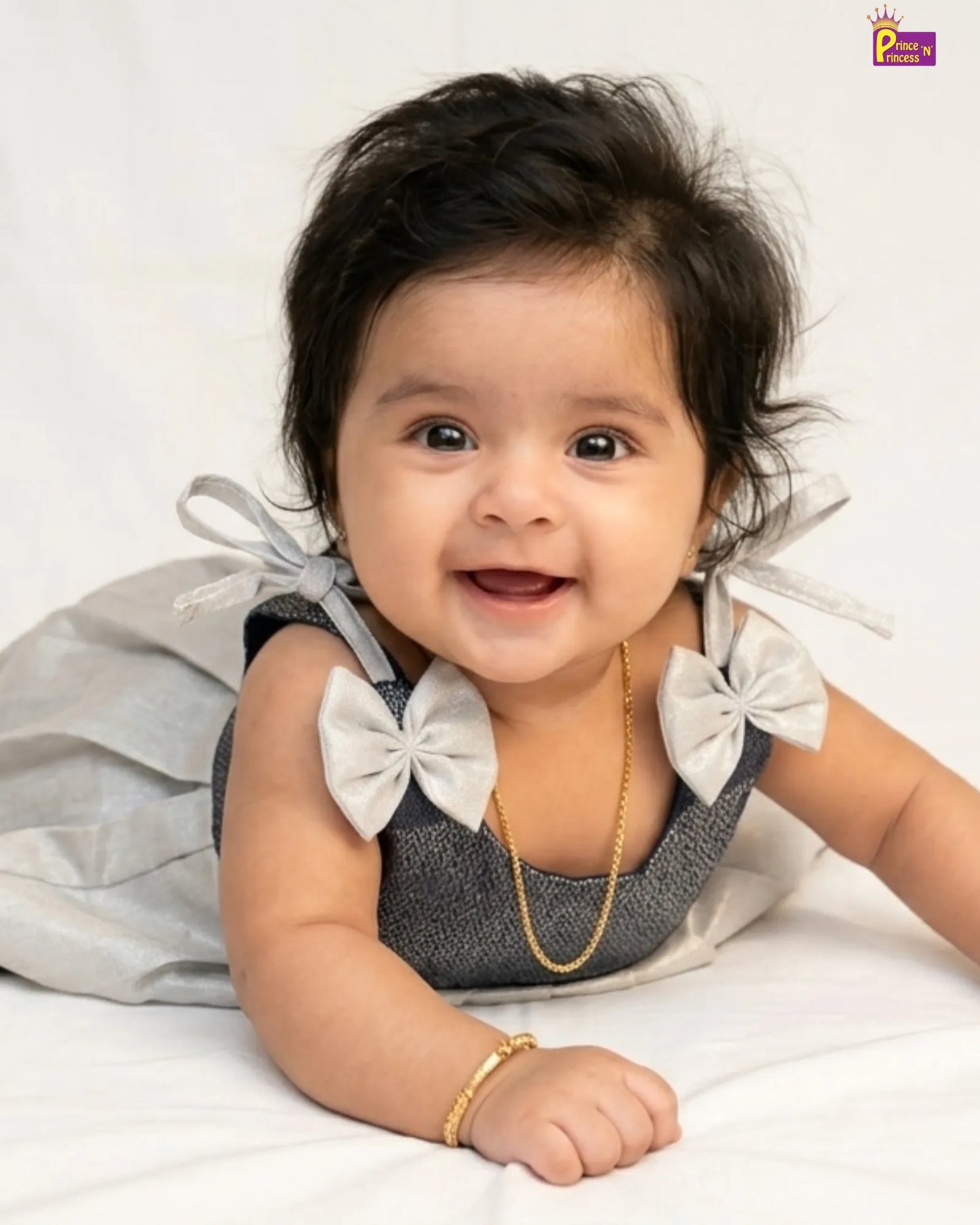 Baby wearing a gray dress with white bows on a white background
