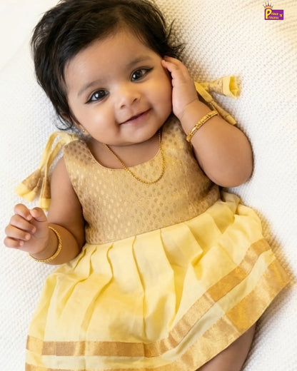 Baby in a yellow traditional outfit with gold jewelry on a white background