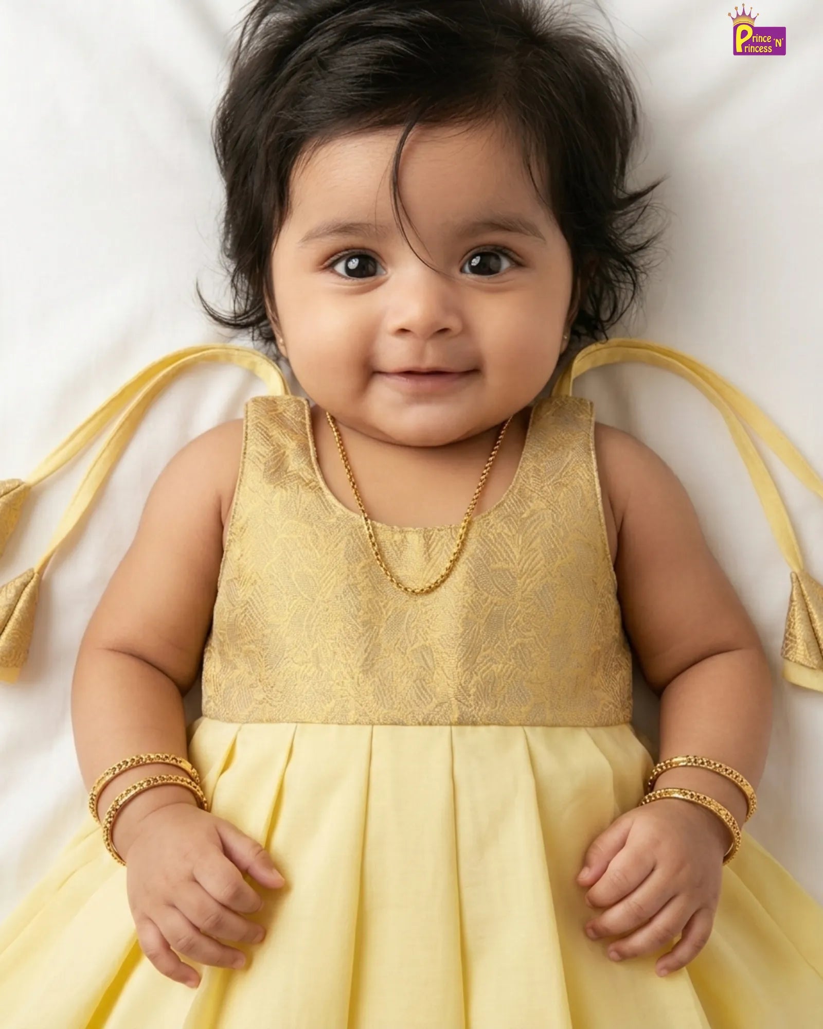 Baby in a yellow dress with gold accents on a white background