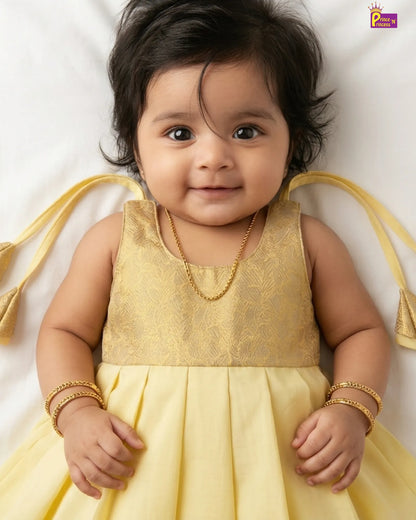 Baby in a yellow dress with gold accents on a white background