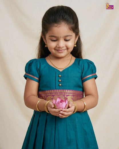 Young girl in a teal traditional outfit holding a pink flower against a beige background