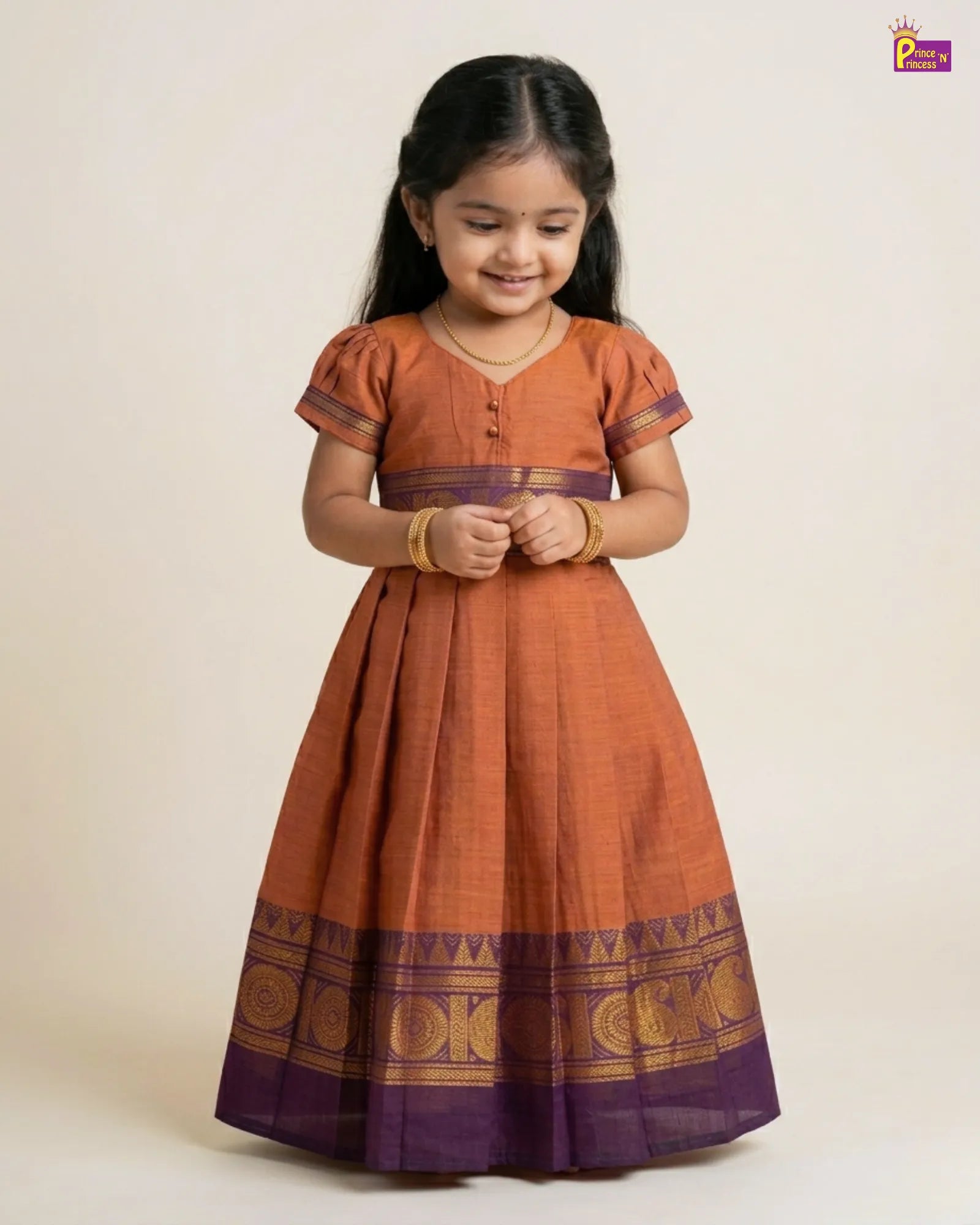 Young girl wearing a traditional orange and purple dress with a plain background