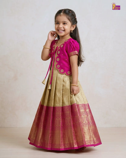 Young girl wearing a traditional outfit with a pink top and gold skirt on a plain background