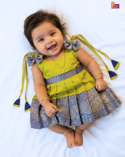 Baby wearing a yellow and blue traditional outfit with tassels on a white background