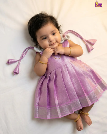 Baby in a purple dress with decorative ribbons on a white background
