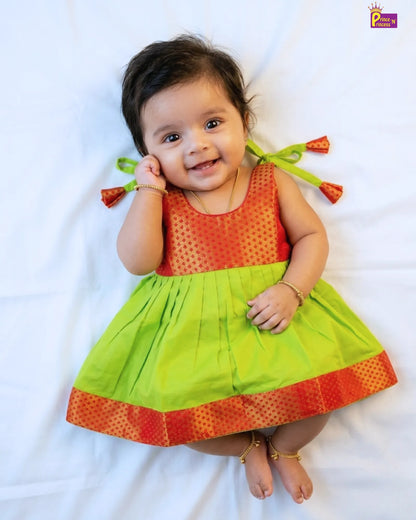 Baby wearing a red and green dress with a white background