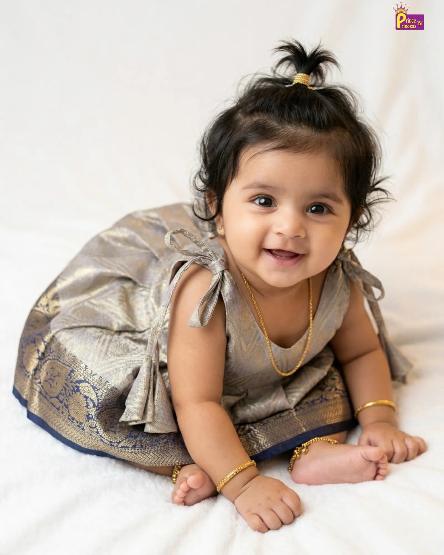 Baby in traditional outfit with gold jewelry on a white background