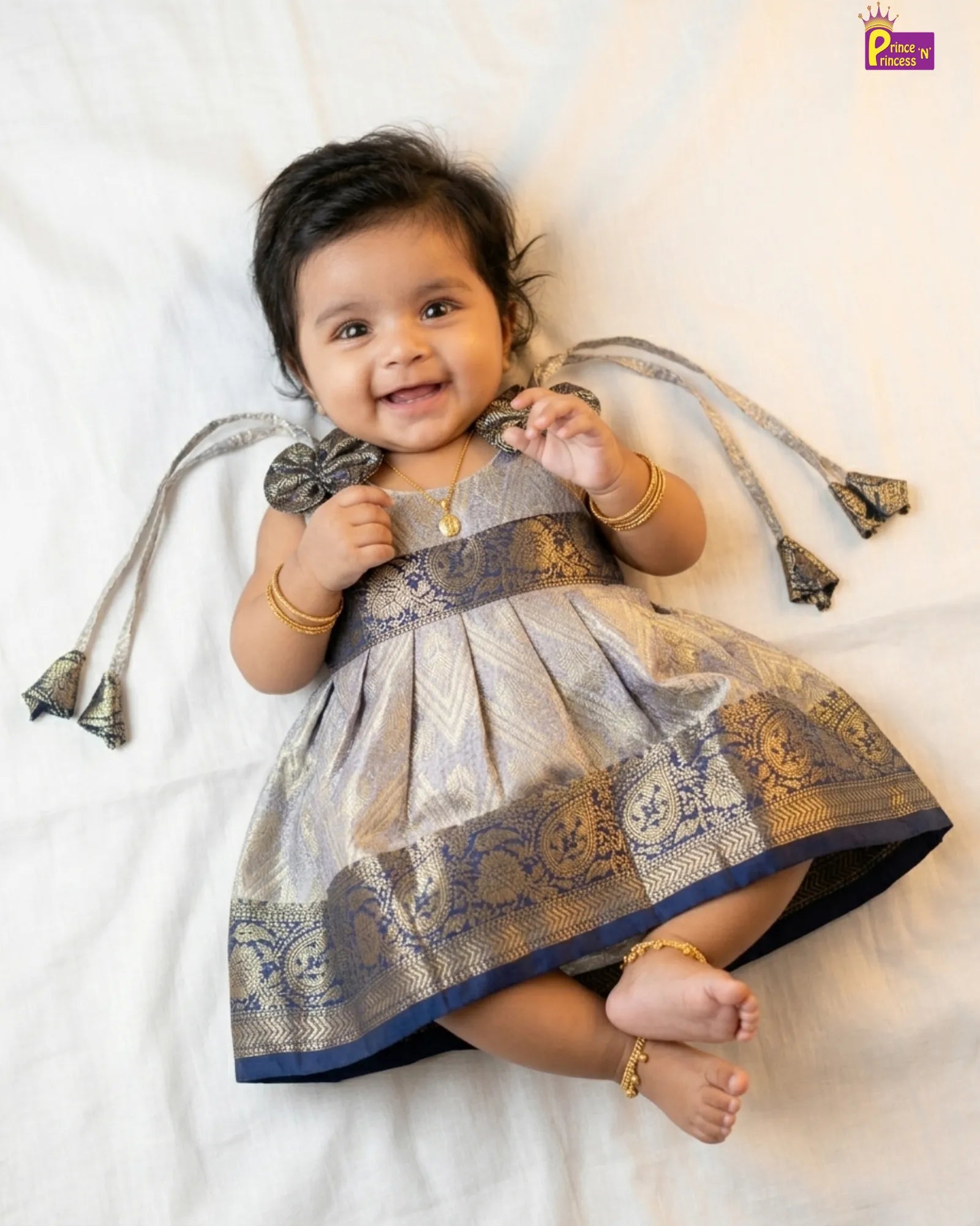 Baby wearing a traditional outfit with decorative elements on a white background