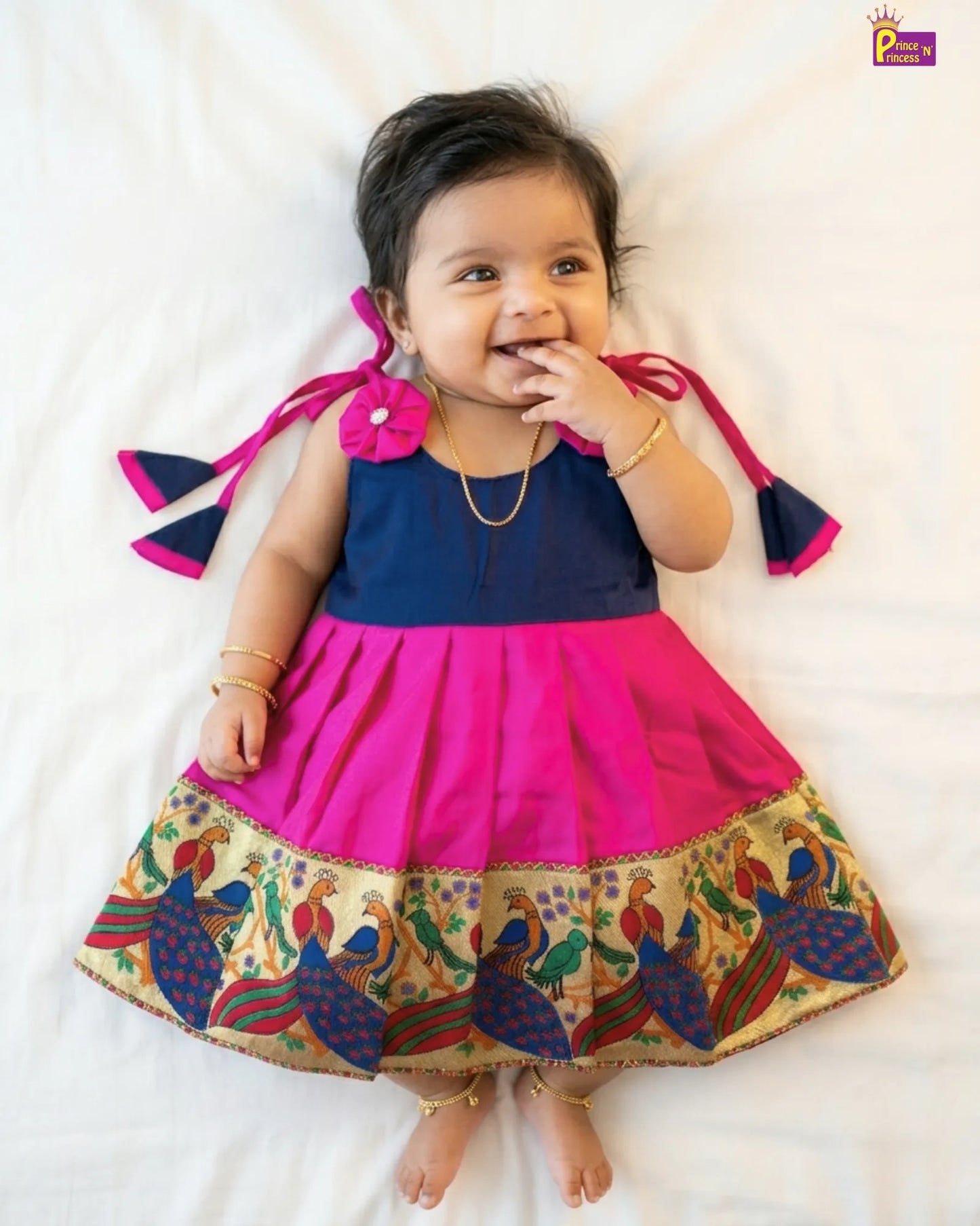 Child wearing a colorful traditional outfit with a pink top and patterned skirt on a white background
