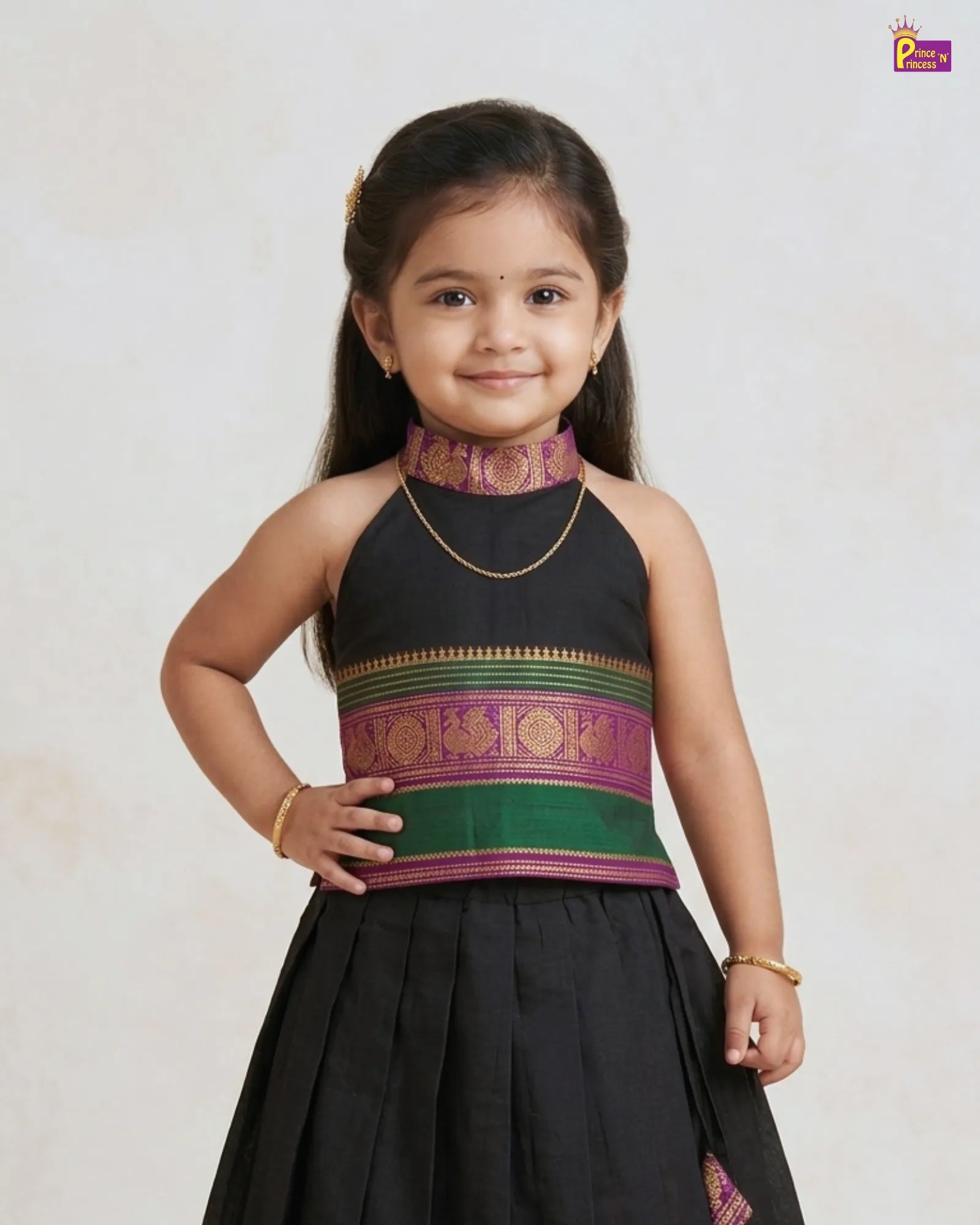 Young girl wearing a traditional black and green blouse with a plain background
