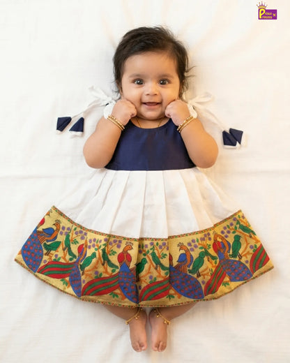 Baby wearing a colorful skirt with peacock design on a white background