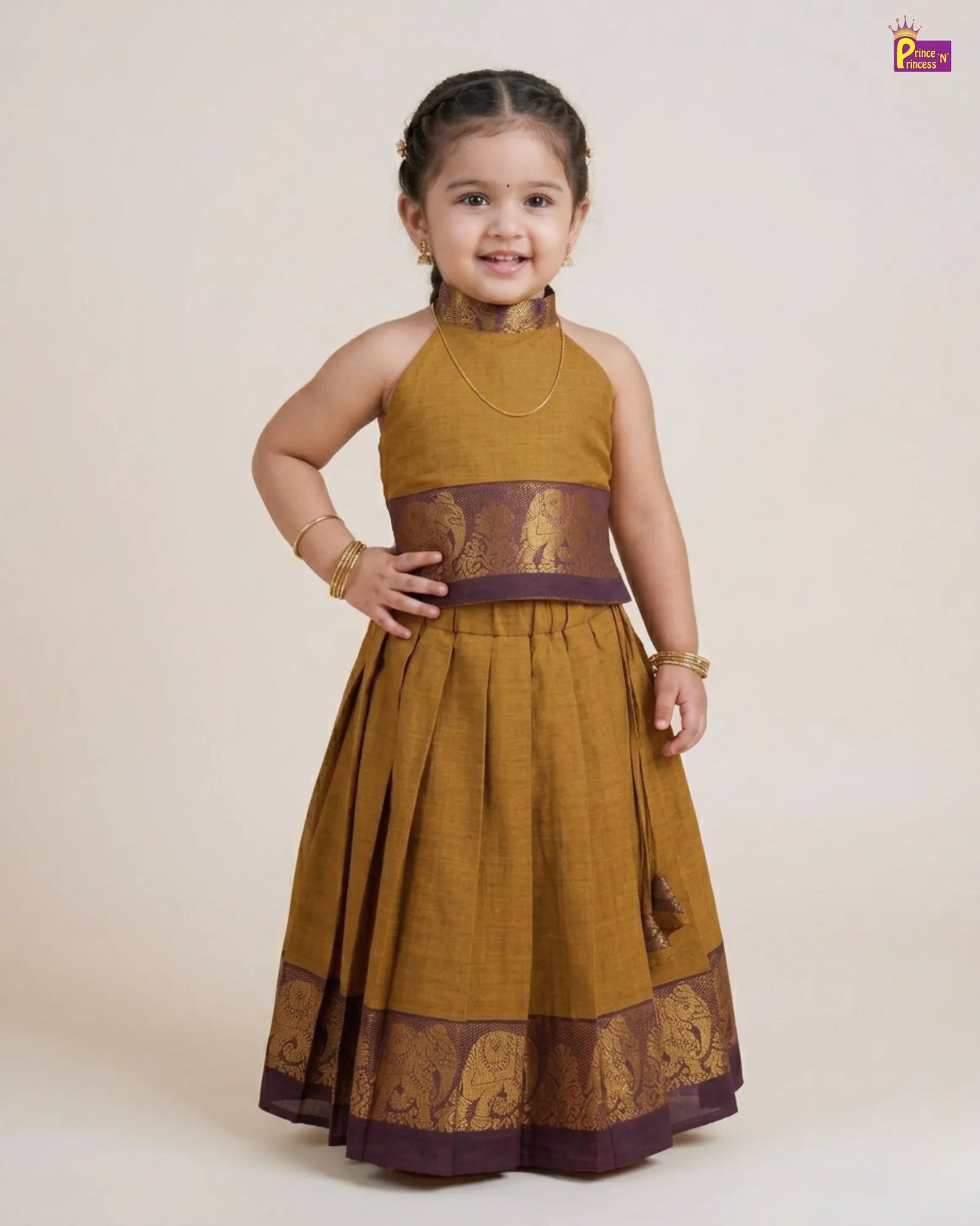 Young girl wearing a traditional mustard yellow and purple dress with intricate patterns on a white background.