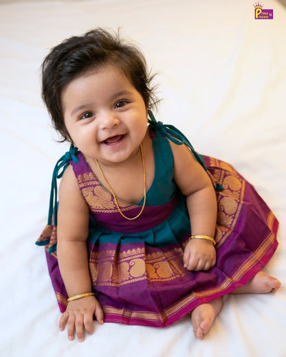 Baby wearing a traditional outfit with a purple and green sari on a white background