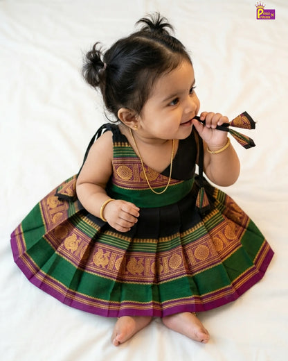 Baby wearing a traditional outfit with green and purple patterns on a white background